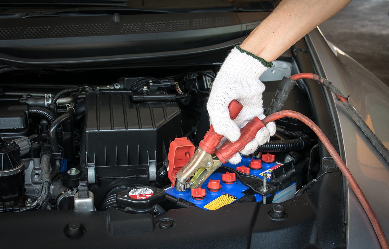 Automotive technician performing Car Jump Start Services on a dead car