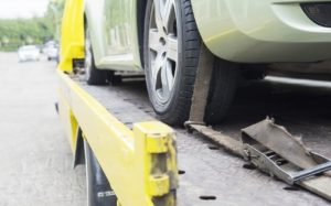 car towing with straps on yellow tow truck